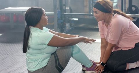 Female trainer assisting client doing core workout, encouraging form and motivation in gym