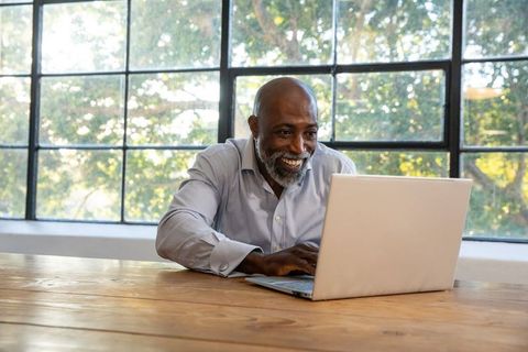 Smiling Senior Professional Using Laptop in Bright Home Office