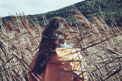 Woman with long hair standing in field of tall grass