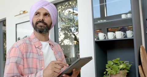 Man in Turban Working from Home with Tablet in Modern Kitchen