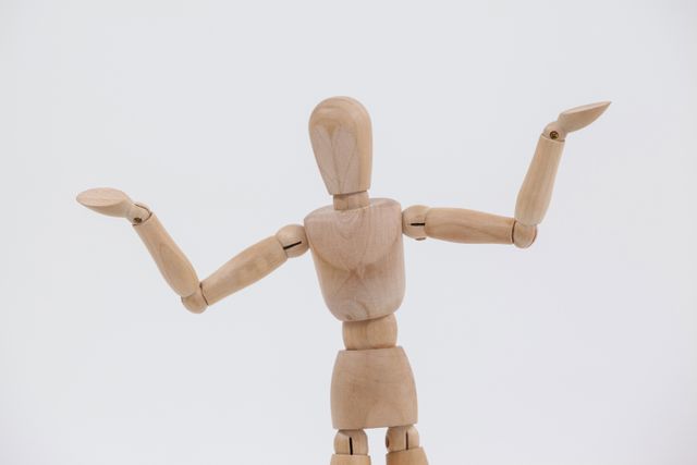 Wooden figurine standing with arms spread against a white background. Useful for illustrating concepts of creativity, design, and art. Ideal for use in educational materials, art tutorials, and creative projects.