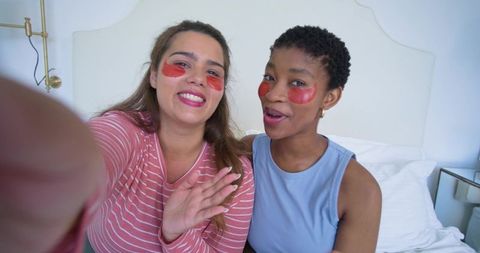 Multicultural friends taking selfie while wearing red under-eye gel patches during at-home skincare
