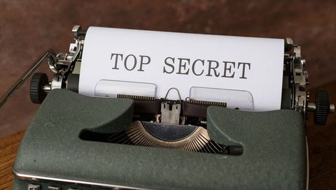 Vintage green manual typewriter typing top secret on paper for retro office concept