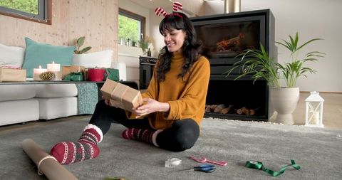 Woman wrapping gift in cozy modern living room for festive occasion