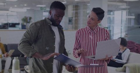 Colleagues collaborating in modern office with laptop and documents