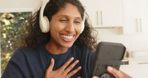 Smiling african american woman wearing headphones during warm heartfelt video call at home