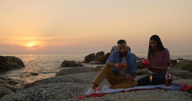 Couple Enjoying Sunset Picnic by Ocean on Rock Surface - Download Free Stock Photos Pikwizard.com