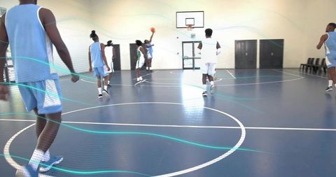 Jumping basketball player reaching hoop in indoor scrimmage showing dynamic team play