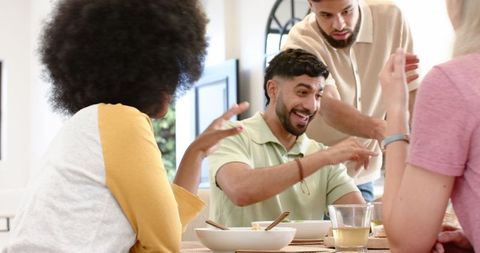 Joyful Friends Sharing Meal and Laughing Together Indoors