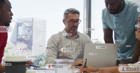 Multiracial business team collaborating around laptop with digital data overlays