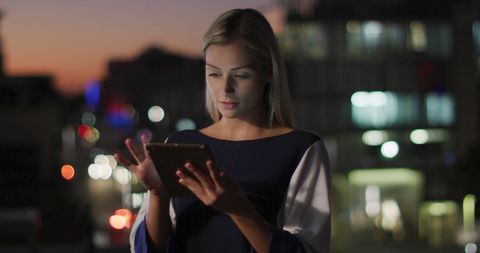 Businesswoman engaging with tablet at night for flexible work