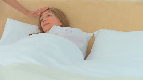 Nurse Taking Temperature of Sick Patient in Bed
