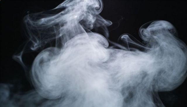 Swirling white smoke waves over black backdrop, abstract mist texture and motion