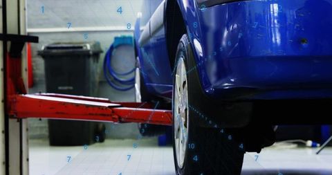 Blue car undergoing wheel inspection on hydraulic lift with digital diagnostics overlay