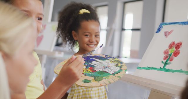 Image of happy diverse girls painting during art lessons at school. primary school education, knowledge and learning concept.