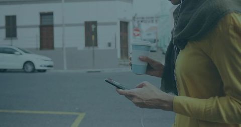 Woman Enjoying Coffee While Using Smartphone on Urban Street