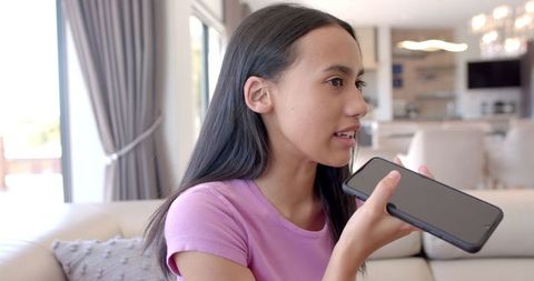 Teen girl using voice assistant on smartphone at home