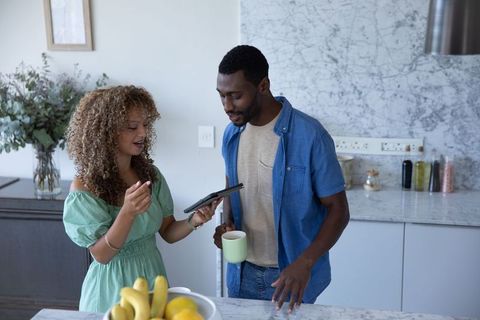 African american couple planning weekly meals on tablet at marble kitchen island