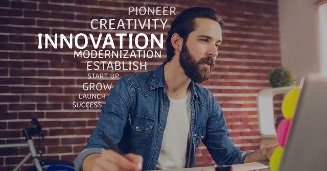 The image depicts a young professional male, focused and working at a desk with a modern setup. Motivational words such as 'innovation', 'creativity', 'modernization', 'success' are featured in the background. This visual is ideal for business, technology, and startup-themed content, showcasing attributes like inspiration, progress, and work ethic.