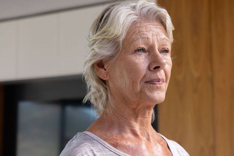 Contemplative senior woman indoors closeup portrait capturing wisdom and calm resilience