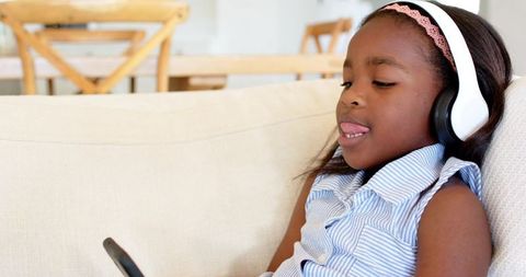 Young Girl Enjoying Music on Headphones While Looking at Smartphone