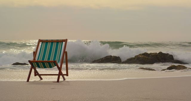Front view of a green and brown wooden sun lounger on the beach with waves at the back