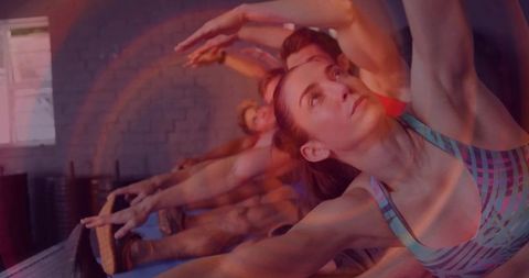 Group pilates class stretching on blue mats with woman reaching in patterned sports bra