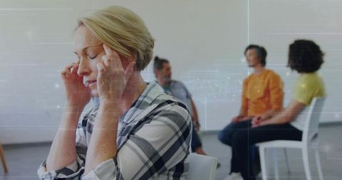 Woman pressing temples during group therapy, practicing mindfulness and stress relief