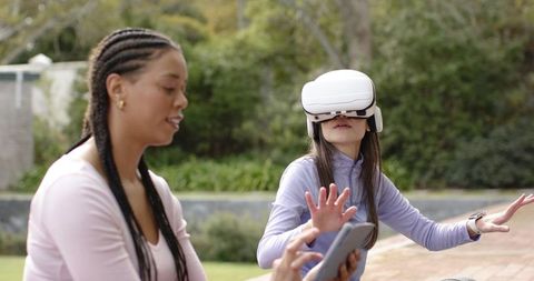 Mentor guiding teen using vr headset outdoors, reaching and exploring immersive learning
