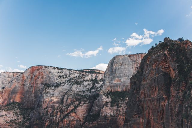 Rocky cliffs stand majestically under clear blue sky, creating stunning natural landscape. Perfect for use in travel promotions, outdoor adventure content, geological studies, nature photography collections, and environmental awareness campaigns.