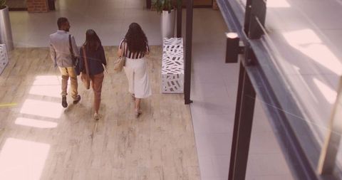 Business professionals walking and collaborating in modern office corridor carrying bags