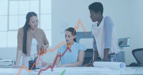 Businesswomen collaborating over blueprints and growth charts in modern bright office