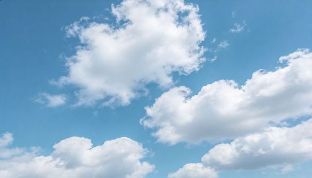 Soft cumulus clouds drifting across bright blue sky for serene sunlit cloudscape background