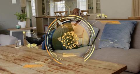 Senior man reading paperback on sofa with ar hud in modern cozy living room
