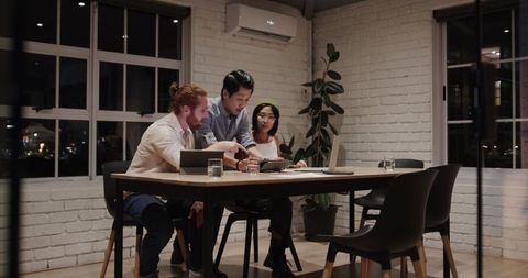 Diverse team collaborating on new project in office late at night