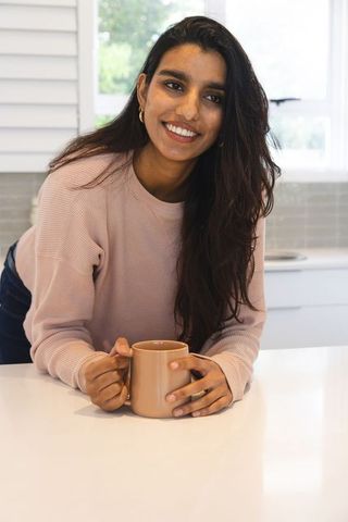 Smiling South Asian Woman in Modern Kitchen Interior with Ceramic Mug