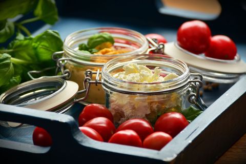 Serving fresh ricotta and cherry tomatoes in glass jars on rustic blue tray for brunch