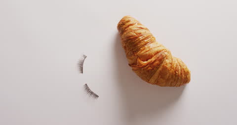 Creative Croissant with Eyelashes on Minimalistic Background