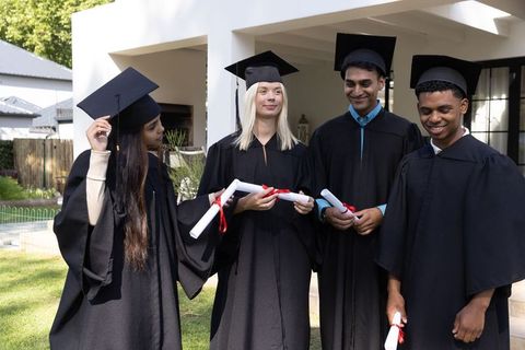 Diverse graduates celebrating success with diplomas and smiles outdoors