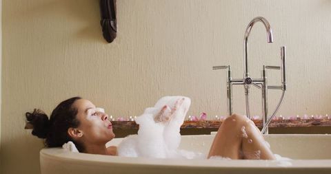 Woman relaxing in foam bath at home spa setting