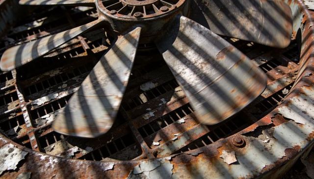 Rotating rusted industrial rooftop fan blades with corroded grille and patina