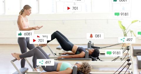 Instructor guiding group performing reformer bridge exercises in sunlit pilates studio