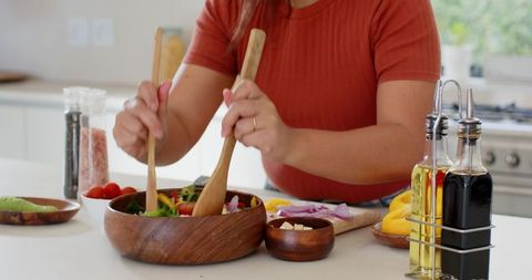 Asian Woman Making Vegetable Salad in Modern Kitchen