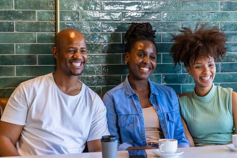 African american friends smiling over coffee in casual cafe with green tile background