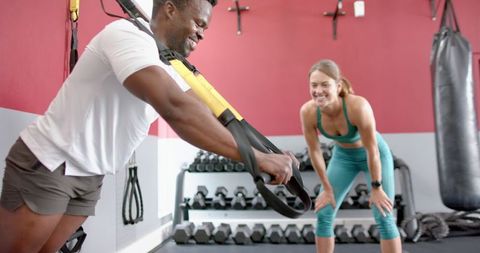 Personal trainer instructing trx workout in gym