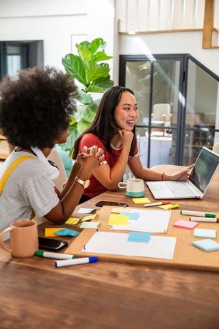 Diverse Female Colleagues Collaborating on Creative Project with Laptop