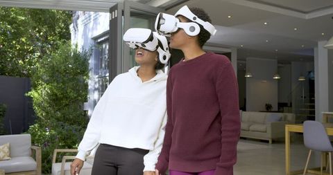 Two Diverse Friends Using VR Headsets at Patio Entrance