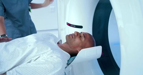 African man undergoing ct head scan in modern radiology suite with laser positioning
