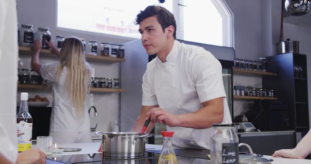 Focused chef stirring pot in modern kitchen - Download Free Stock Images Pikwizard.com