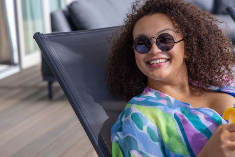 Smiling african american woman relaxing on resort deck in colorful cover-up